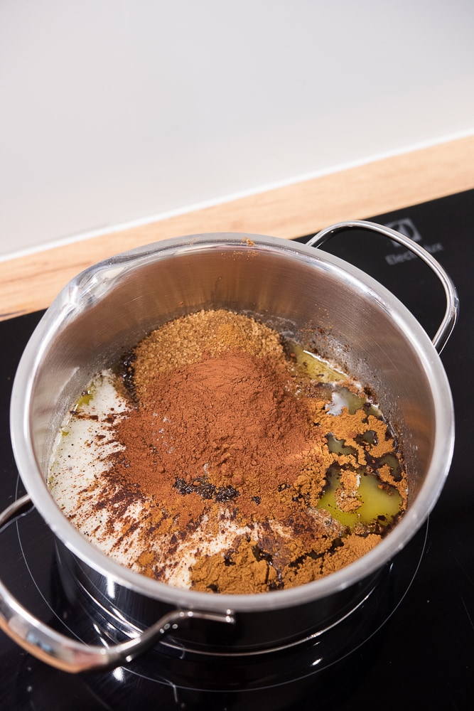 Składniki na piernik w rondelku - rozpuszczone masło, cukier, kakao, przyprawa do piernika, cynamon i miód.